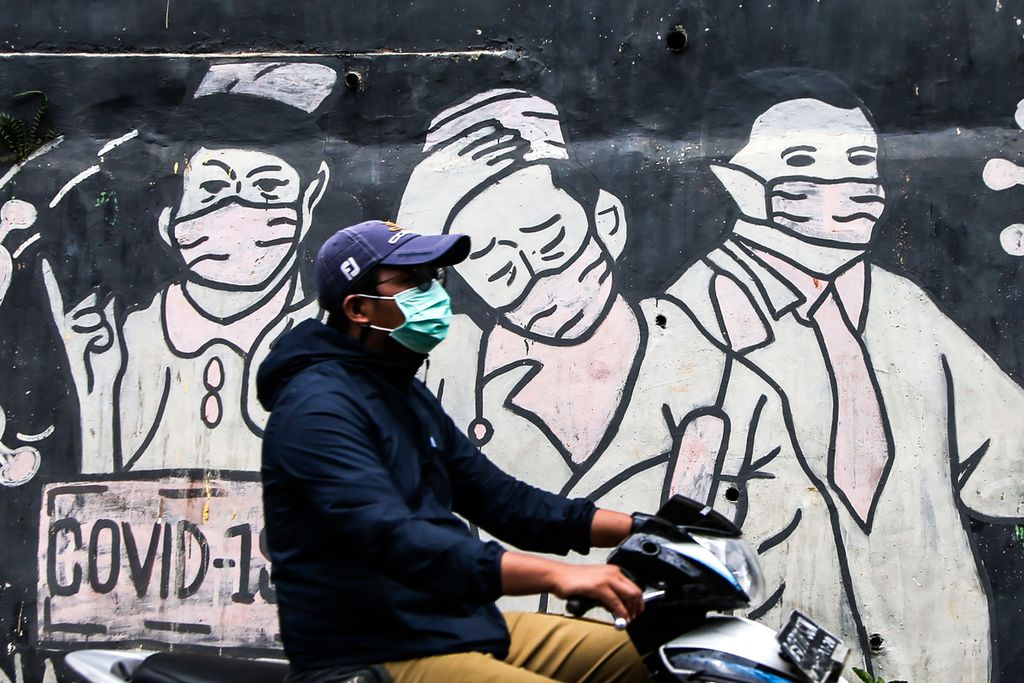 Pengguna jalan melintas di depan mural bertema Covid-19 di kawasan Limo, Depok, Jawa Barat, Minggu (6/2/2022). Di tengah merebaknya varian Omicron, lonjakan kasus Covid-19 di Indonesia tidak terbendung. 