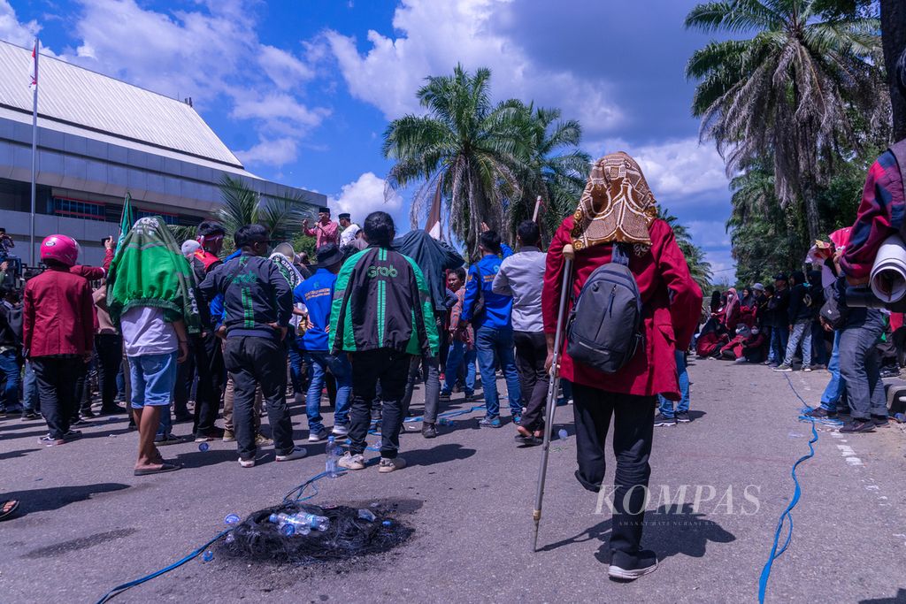 Seorang mahasiswa dengan tongkat penyangga mengikuti aksi nasional pada Senin (11/4/2022) di Kendari, Sulawesi Tenggara, bersama ribuan mahasiswa lainnya.