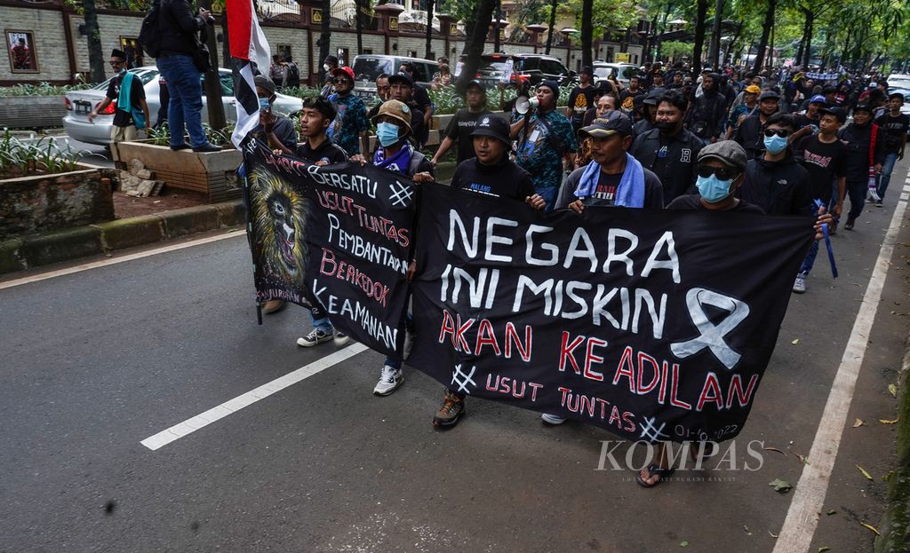 Barisan suporter Aremania berjalan bersama dengan para penyintas dan keluarga korban Tragedi Kanjuruhan ketika mendatangi Markas Besar Kepolisian Negara Republik Indonesia, Jakarta, untuk mempertanyakan kelanjutan pelaporan mereka atas tragedi kemanusiaan tersebut, Sabtu (19/11/2022). 