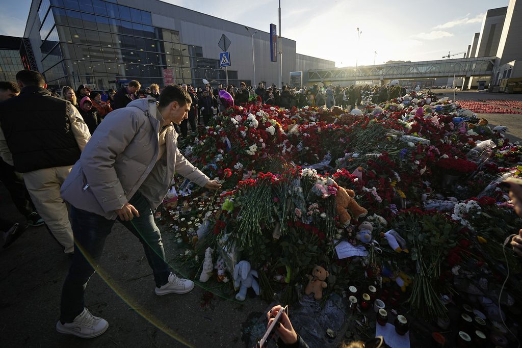 Warga meletakkan bunga di tugu peringatan darurat di depan Balai Kota Crocus di pinggiran Moskwa, Rusia, pada 25 Maret 2024. 