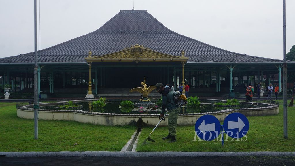 Seorang petugas memotong rumput dalam rangka kerja bakti di Pura Mangkunegaran, Kota Surakarta, Jawa Tengah, Jumat (25/3/2022). Kerja bakti tersebut merupakan bagian dari persiapan diadakannya rangkaian acara presidensi G20 di kota tersebut.