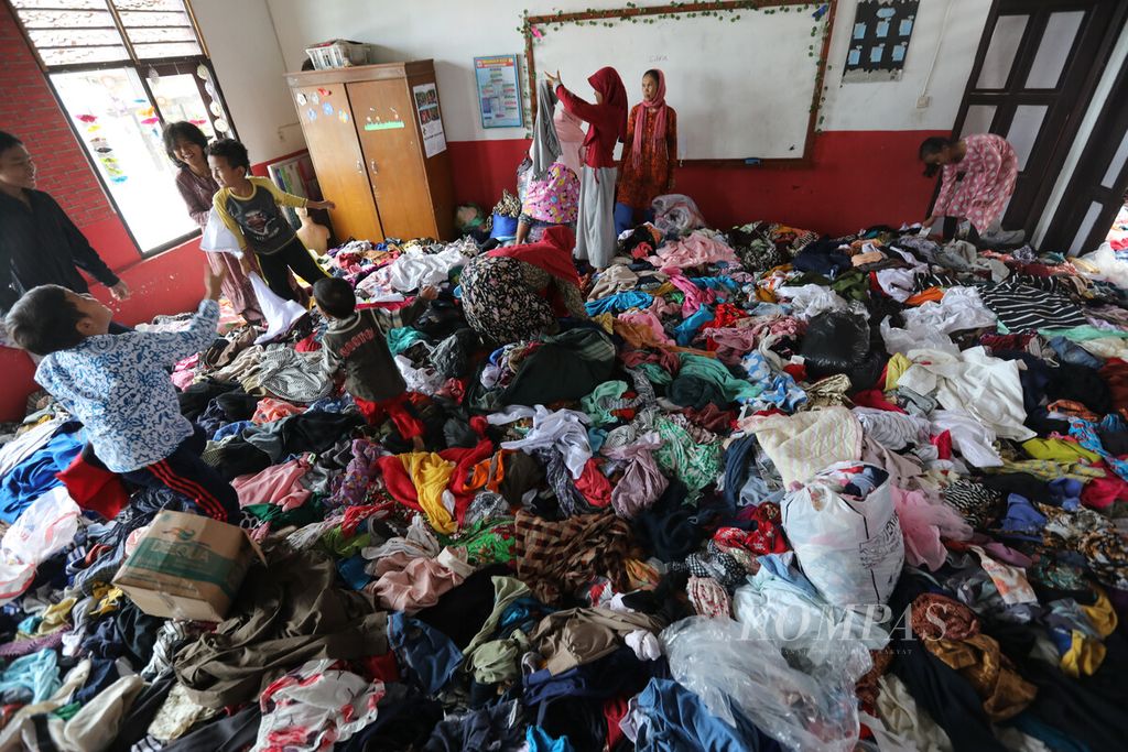 Korban gempa berburu baju bekas yang dikumpulkan di SDN Gintung, Desa Gintung, Kecamatan Cugenang, Kabupaten Cianjur, Jawa Barat, Minggu (4/12/2022). 