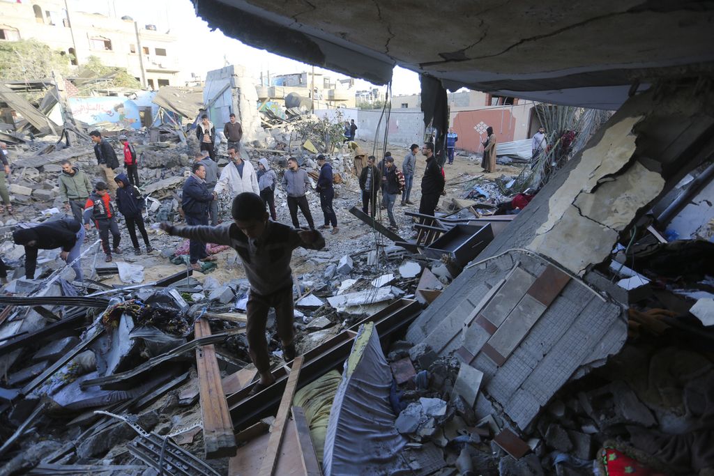 Warga Palestina berdiri di dekat bangunan yang hancur akibat pemboman Israel semalam di Rafah, Jalur Gaza, Jumat (24/11/2023). 