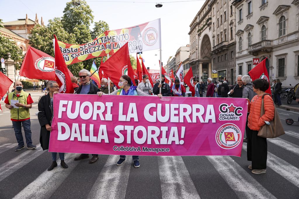 Para peserta pawai May Day menunjukkan poster yang bertuliskan ajakan untuk menghentikan perang dan mendorong perdamaian di Ukraina dalam aksi di Milan, Italia, Minggu (1/5/2022).