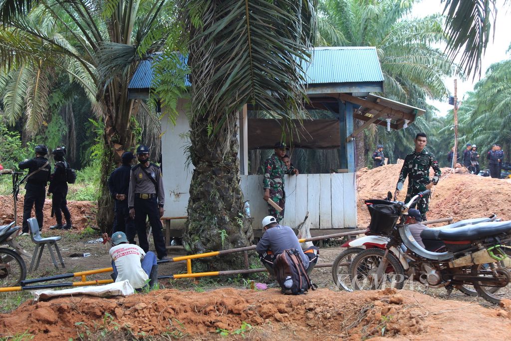 Buruh sawit yang sedang bekerja pada Kamis (12/10/2023) dijaga ketat oleh aparat keamanan di Desa Bangkal, Kabupaten Seruyan, Kalimantan Tengah. Dalam situasi ini, baik warga maupun pekerja sama-sama resah.
