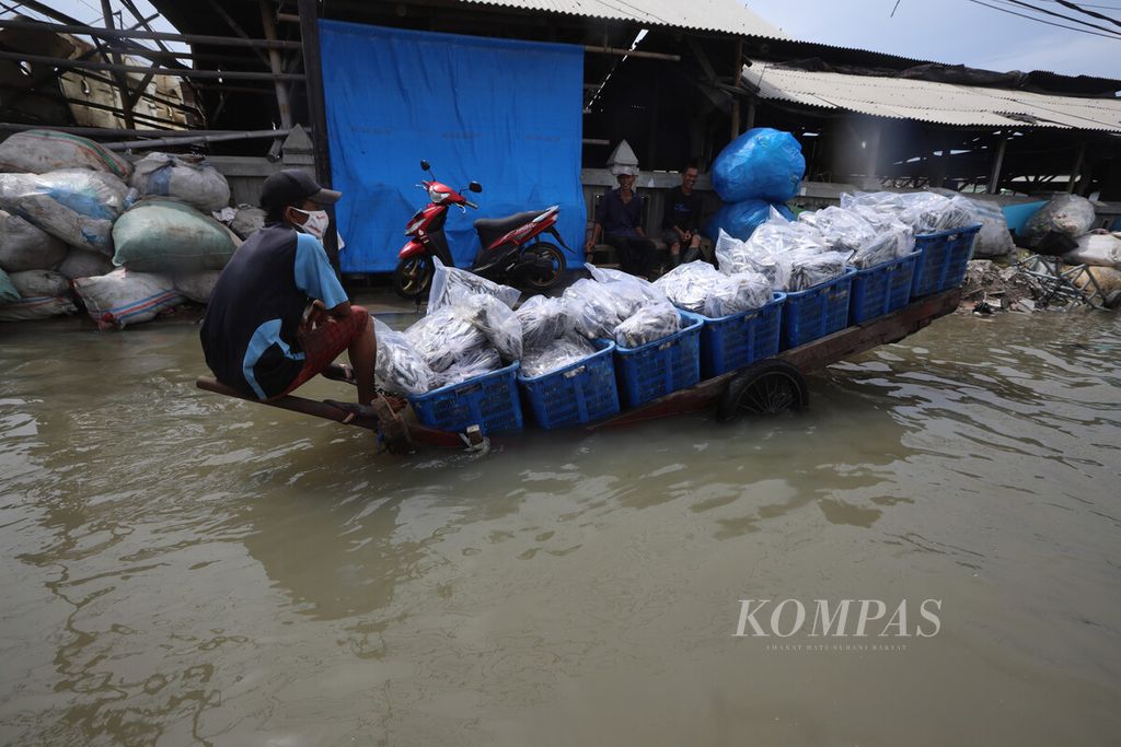 Penjual air keliling beristirahat saat banjir rob melanda kawasan Muara Angke, Pluit, Penjaringan, Jakarta Utara, Senin (16//11/2020). Banjir tersebut menggenangi permukiman dan pusat pengasinan ikan di kawasan tersebut. Banjir juga menghambat akses menuju Pelabuhan Muara Angke.