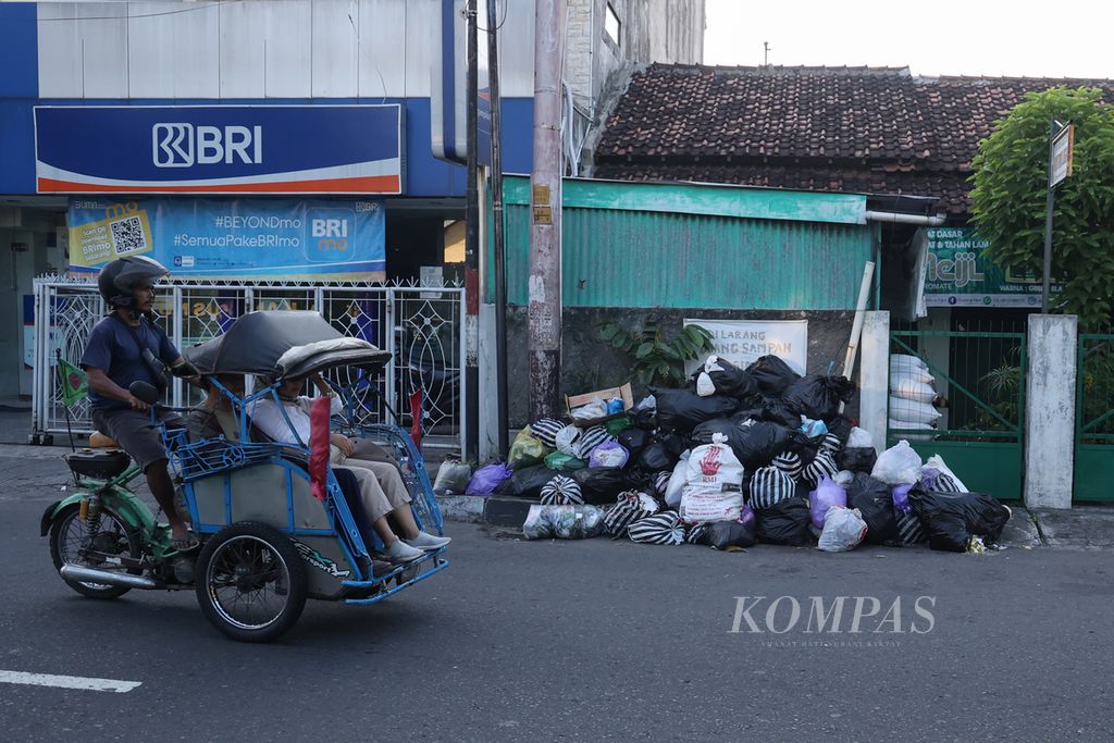 Pengguna becak melintas di depan tumpukan sampah di Jalan Letjen Suprapto, Kota Yogyakarta, Sabtu (4/5/2024).