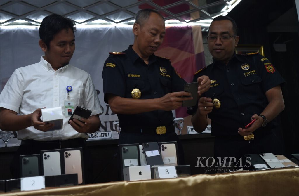 Kepala Kanwil Bea Cukai Jatim 1 M Purwantoro (tengah) menunjukkan barang bukti usaha jasa titipan berupa HP iPhone 11 yang disita dari penumpang pesawat internasional di Kantor Pengawasan dan Pelayanan Bea dan Cukai Tipe Madya Pabean Juanda, Sidoarjo, Jawa Timur, Kamis (10/10/2019).  