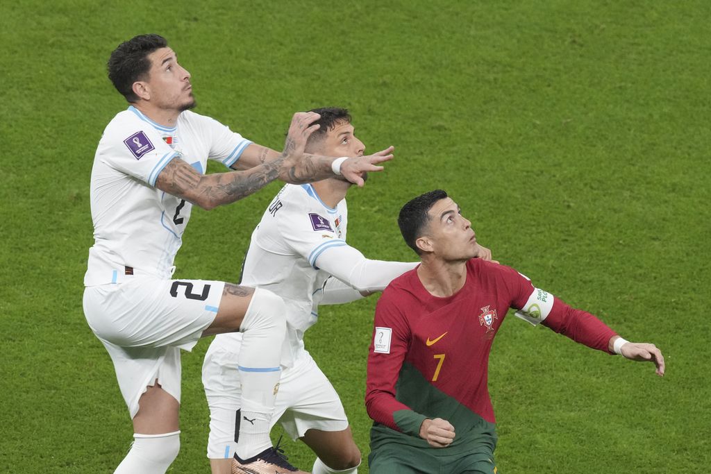 Pemain Portugal, Cristiano Ronaldo (kanan), dijaga pemain Uruguay saat bertanding di fase Grup H Piala Dunia Qatar di Stadion Iconic, Lusail, Selasa (29/11/2022) dini hari WIB.