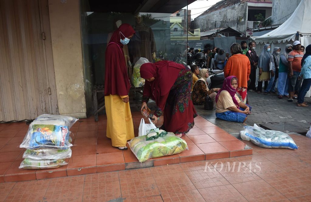 Warga merapikan barang belanjaannya saat Operasi Pasar Lumbung Pangan Jawa Timur di Pasar Pucang Anom, Kota Surabaya, Minggu (4/12/2022). 