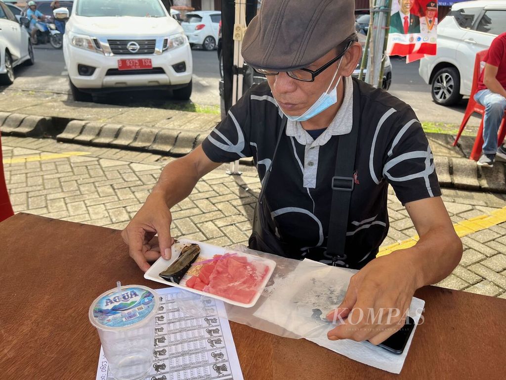 Seorang pengunjung Festival Tuna Sulawesi Utara membuka paket sashimi yang diberikan panitia di Manado, Sulawesi Utara, Sabtu (17/9/2022). 