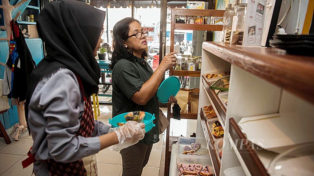 Pramuniaga melayani pembeli roti yang membawa wadah makanan mereka sendiri di Kebun Roti, Desa Caturtunggal, Depok, Sleman, DI Yogyakarta, Kamis (24/1).