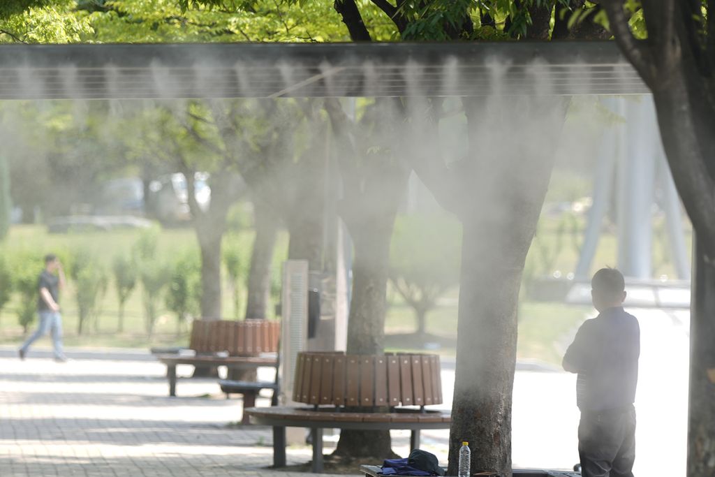 Seorang pria menyejukkan diri di stasiun penyemprotan air yang dipasang pemerintah kota karena gelombang panas di Seoul, Korea Selatan, Kamis (20/6/2024). 