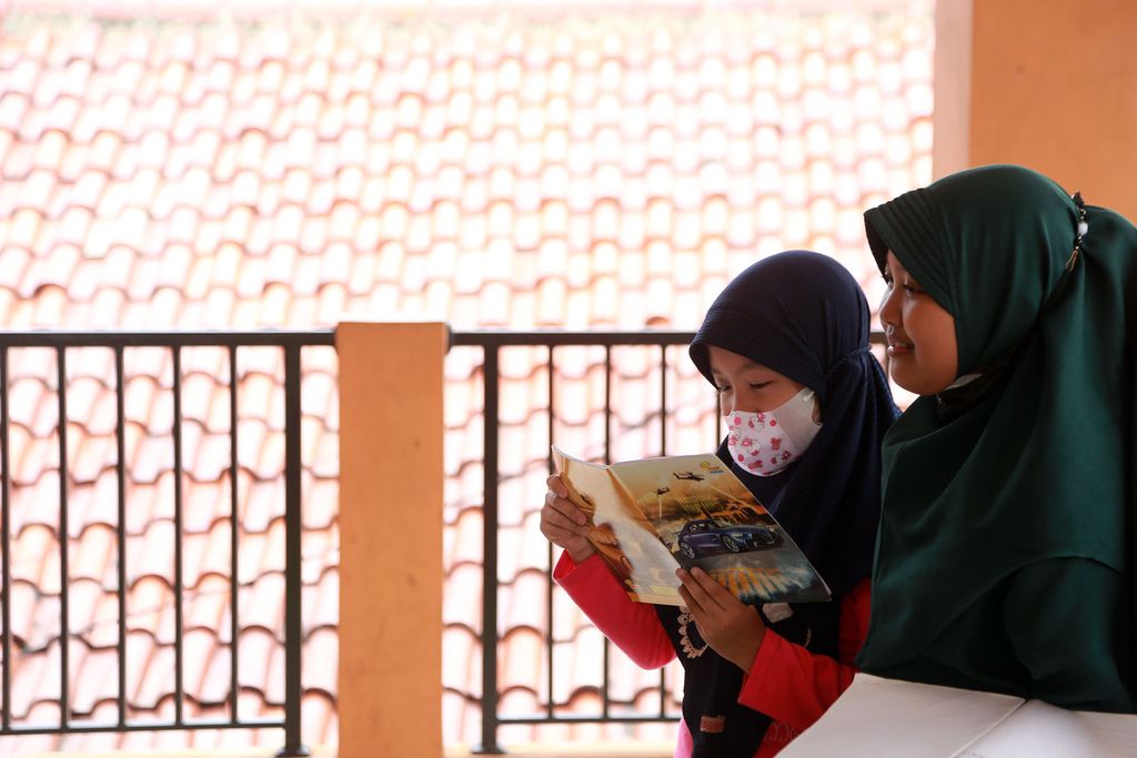 Anak - anak membacakan tugas kelasnya di Taman Baca Masyarakat Kampung Buku, Ciracas, Jakarta Timur, Rabu (21/12/2022). 