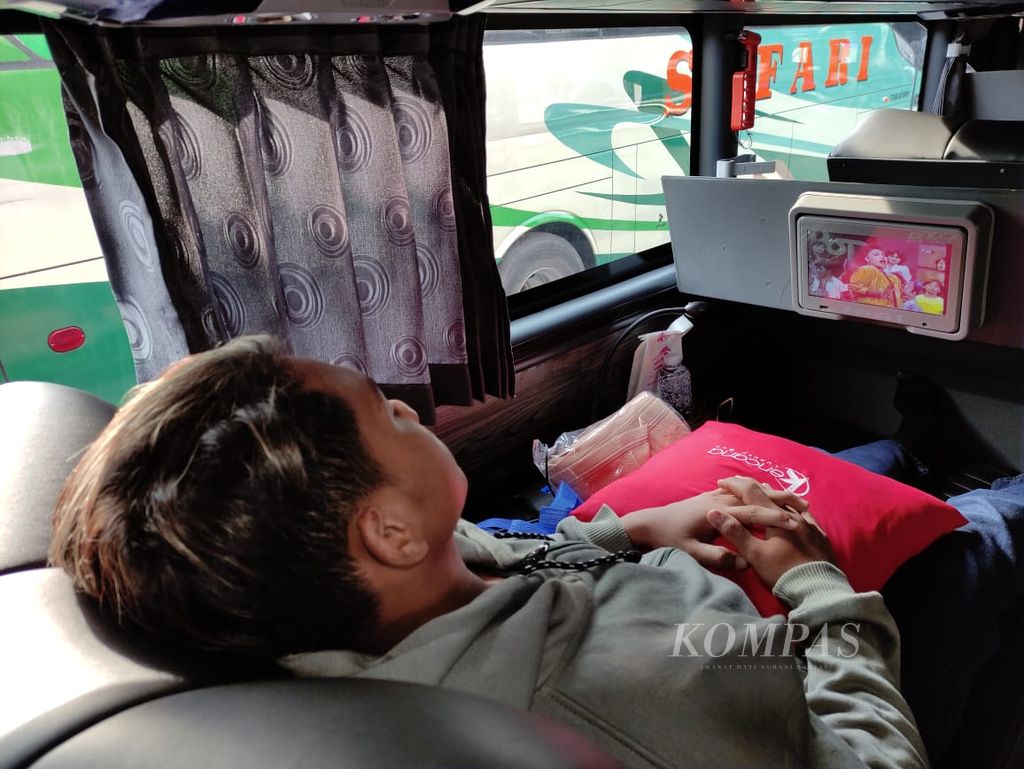 Penumpang kelas <i>sleeper</i> Kencana menikmati tayangan televisi menjelang keberangkatan bus tersebut di Jakarta, Jumat (15/12/2023).