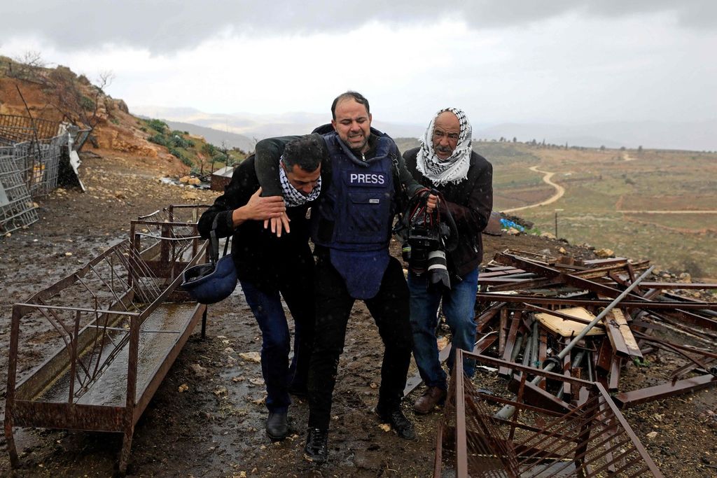 Seorang jurnalis foto, Ayman Nobani (tengah), dipapah oleh dua warga Palestina setelah terluka oleh tembakan aparat keamanan Israel saat ia meliput bentrokan di Desa Duma, wilayah pendudukan Tepi Barat, 2 Februari 2023. 