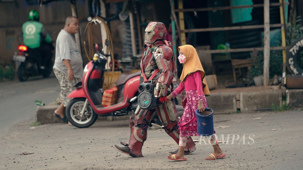 Warga berpakaian Iron Man menggandeng seorang anak mengamen di Jatibening, Kota Bekasi, Jawa Barat, Kamis (17/3/2022).  