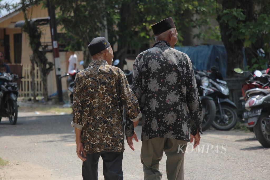 Dua pemain rapai pasee, Teuku Muhammad Daud (88) dan Nasruddin (69), berjalan bersama seusai diwawancarai pada Rabu, (22/6/2023) di Glumpang VII, Kecamatan Matang Kuli, Kabupaten Aceh Utara. Keduanya adalah tokoh yang melestarikan kesenian rapai pasee.
