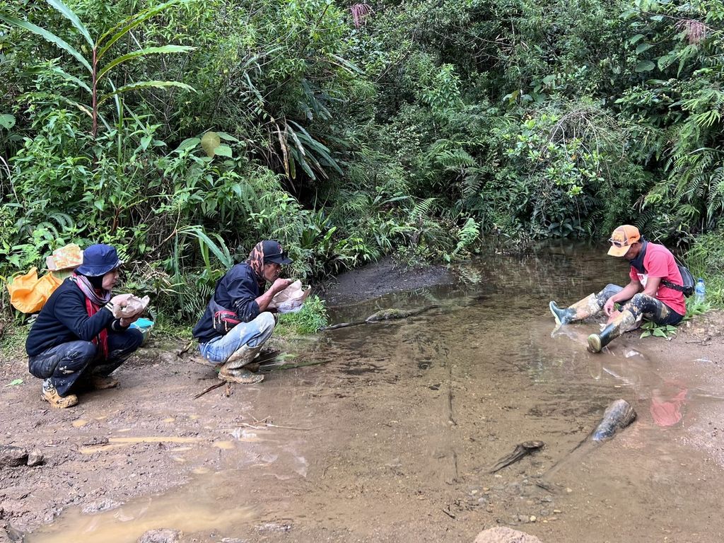 Wartawan <i>Kompas</i> Reny Sri Ayu dan dua pengojek makan siang di tepi sungai dalam perjalanan Mabusa-Se'pon, Seko, Luwu Utara, Sulawesi Selatan, yang medannya sulit, Senin (4/7/2022). Di jalur ini pengendara harus membawa bekal karena tak ada warung.
