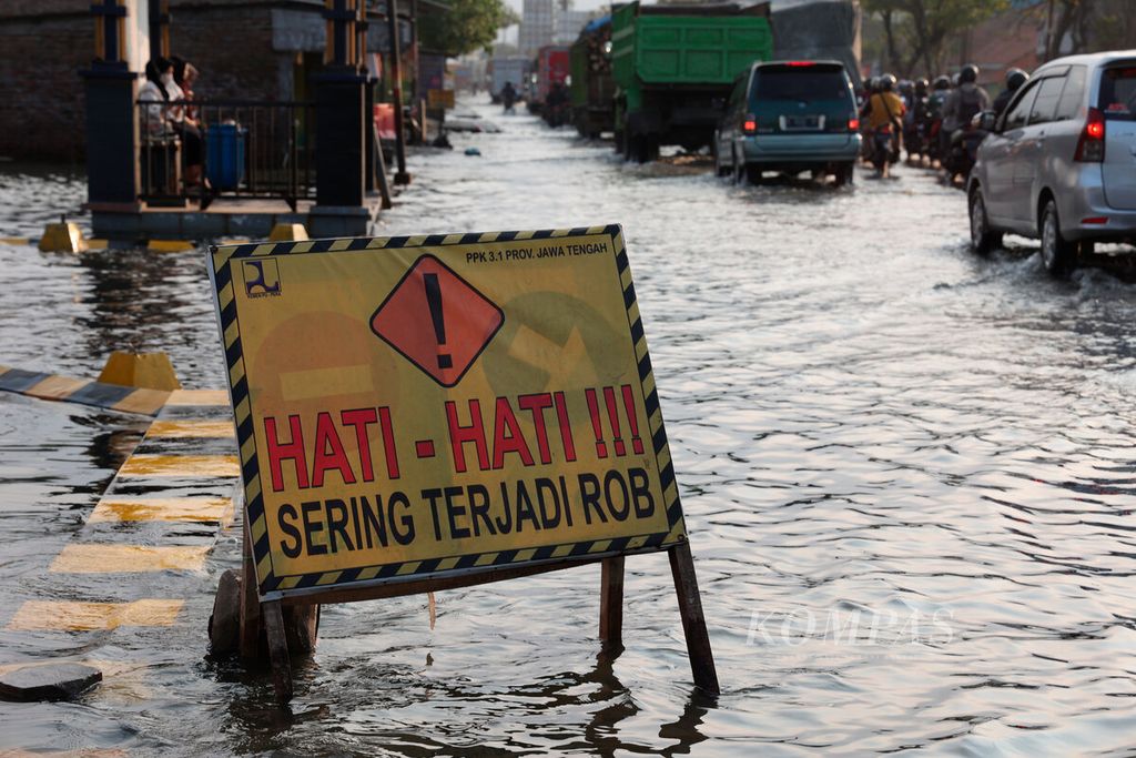 Tanda peringatan bagi pengendara tentang genangan pasang air laut yang sering membanjiri jalur pantai utara di Kecamatan Sayung, Kabupaten Demak, Jawa Tengah, Selasa (16/5/2023). 