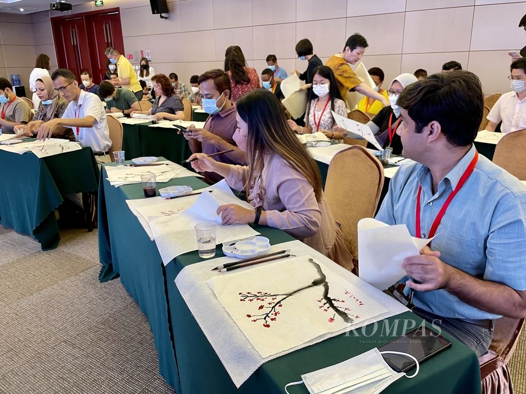 Wartawan-wartawan asing dari Asia, Pasifik, dan Afrika sedang belajar melukis tradisional China dengan menggunakan kuas berbulu musang, kertas beras, dan tinta hitam di Beijing, China, 4 Juli 2022.