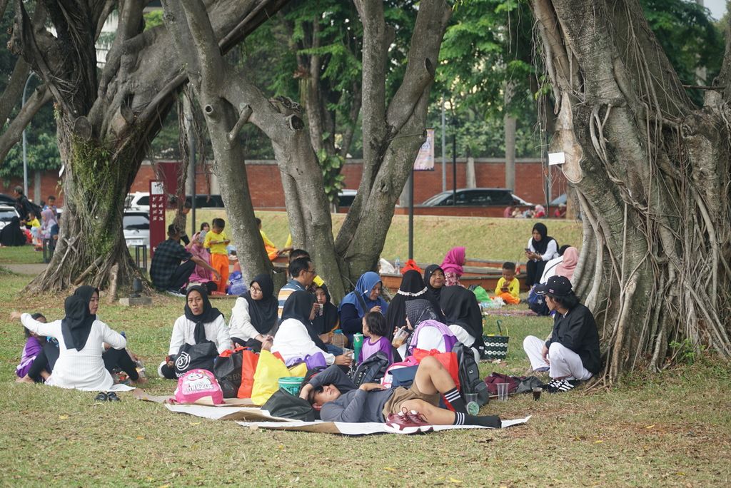 Warga piknik atau istirahat di taman sekitar Tugu Api Pancasila, Taman Mini Indonesia Indah (TMII), Jakarta Timur, DKI Jakarta, Senin (25/12/2023).
