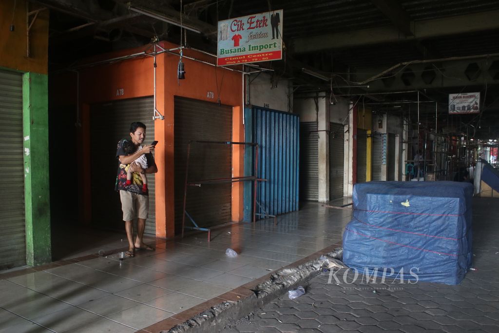 Salah satu warga berdiri di antara kios-kios yang tutup di Pasar Cimol Gedebage, Kecamatan Panyileukan, Kota Bandung, Rabu (22/3/2023). Ribuan kios di pasar tersebut ditutup pedagang pascalarangan impor pakaian bekas oleh pemerintah.