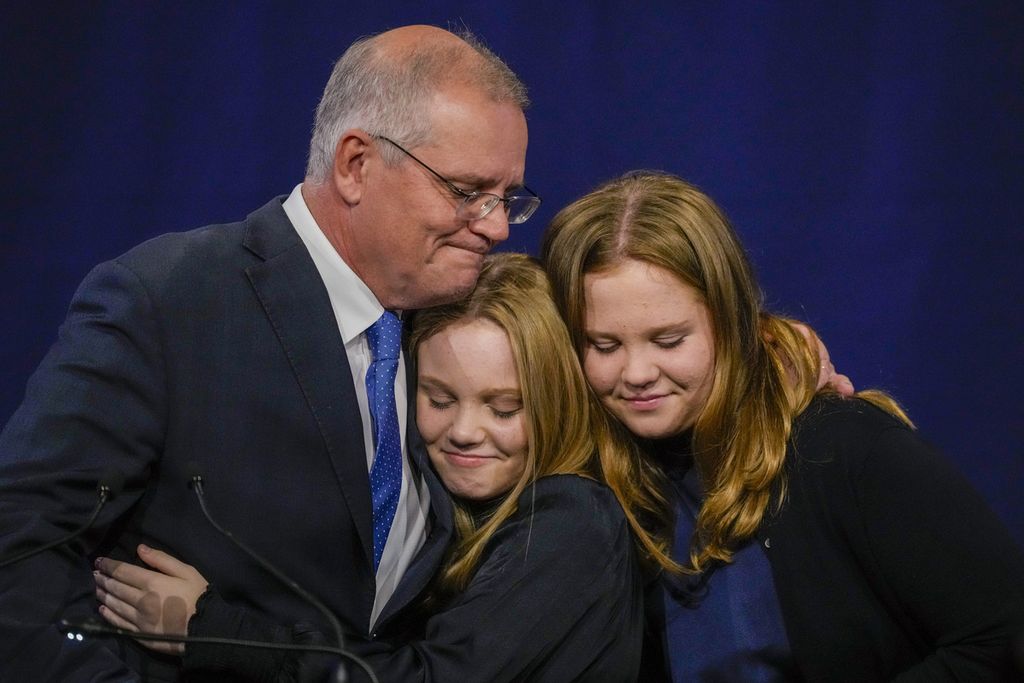 Perdana Menteri Australia Scott Morrison merangkul dua anak perempuannya, Lily dan Abbey, di markas Partai Liberal di Sydney, Sabtu (21/5/2022). Ia mengakui kekalahan dari oposisi dalam pemilu yang berlangsung Sabtu ini. 