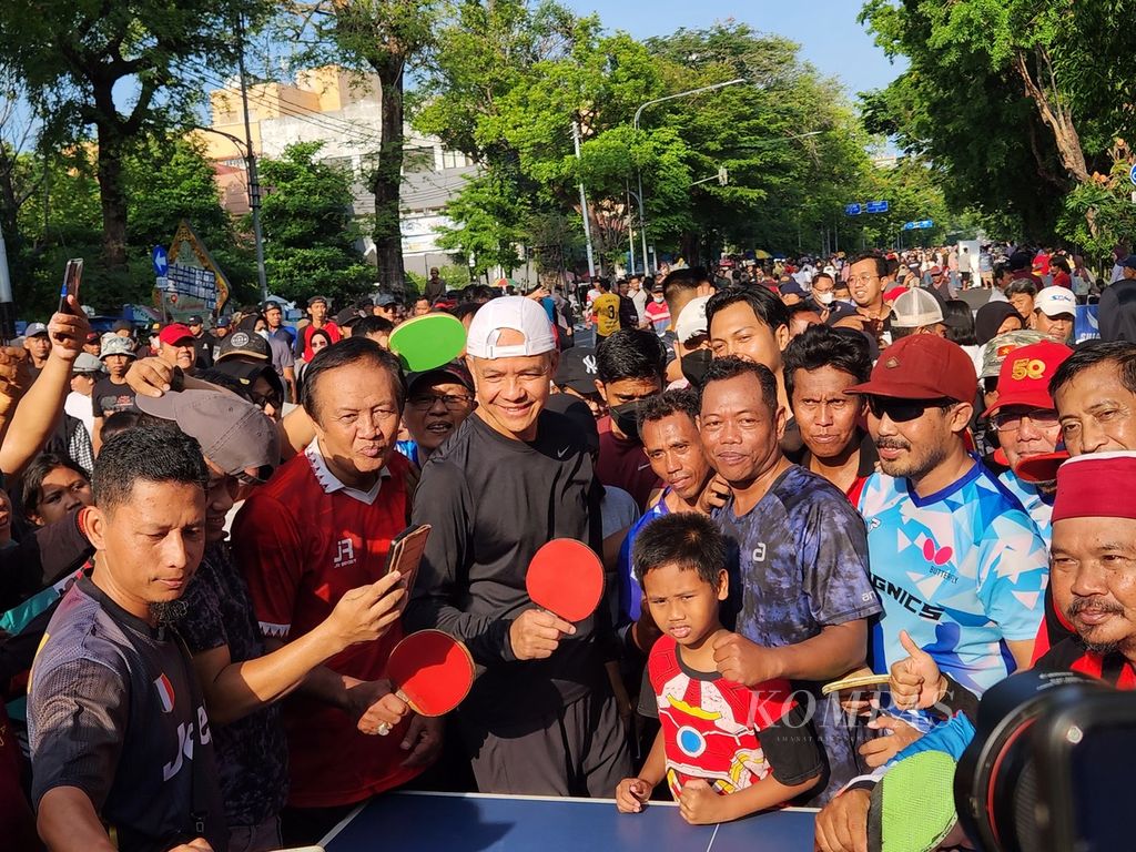 Capres nomor urut 3, Ganjar Pranowo (tengah), berfoto bersama warga setelah bermain tenis meja sewaktu mengunjungi <i>car free day</i> di Kota Surakarta, Jawa Tengah, Minggu (24/12/2023). 