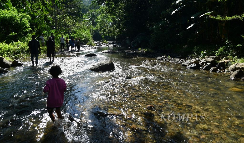 Warga berjalan melintasi aliran Sungai Lowo Lo’o di Desa Bhera, Kecamatan Mego, Kabupaten Sikka, Nusa Tenggara Timur, Selasa (14/5/2024). 