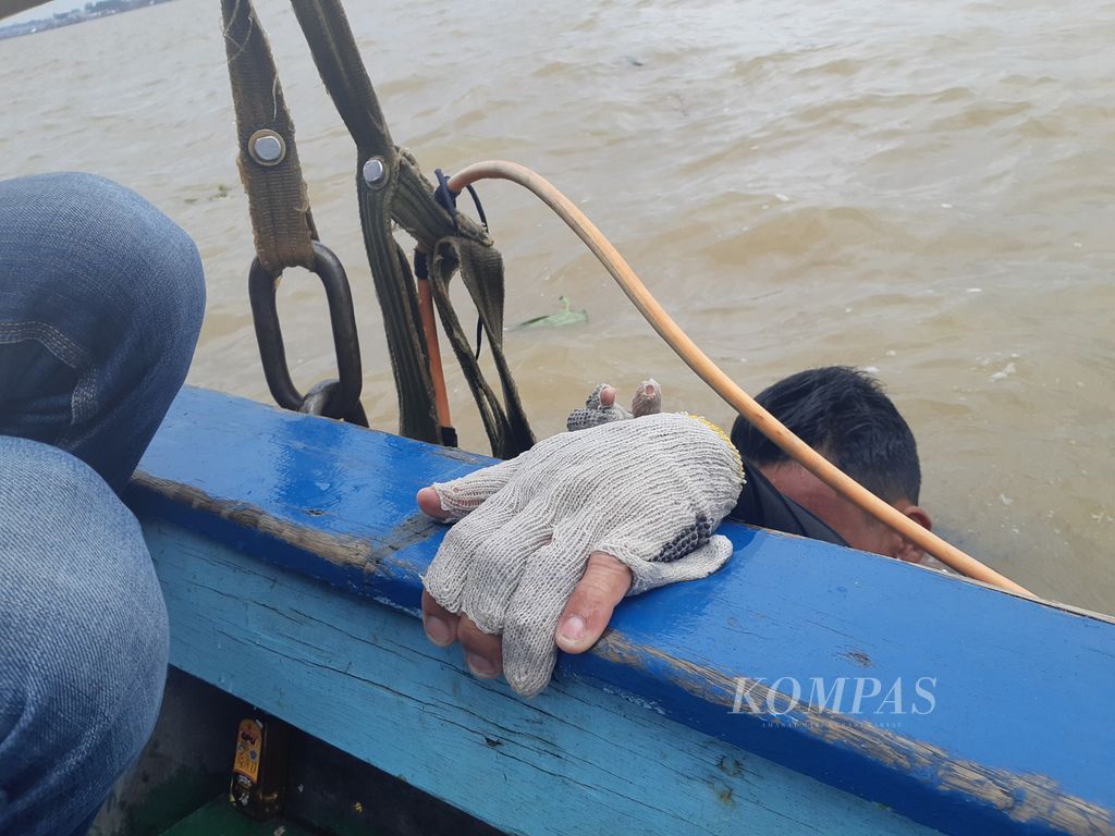 Seorang penyelam menaiki kapal setelah satu jam menyelam di Sungai Musi, Palembang, Sumatera Selatan, untuk mencari harta karun di dasar sungai, Kamis (28/10/2021). 