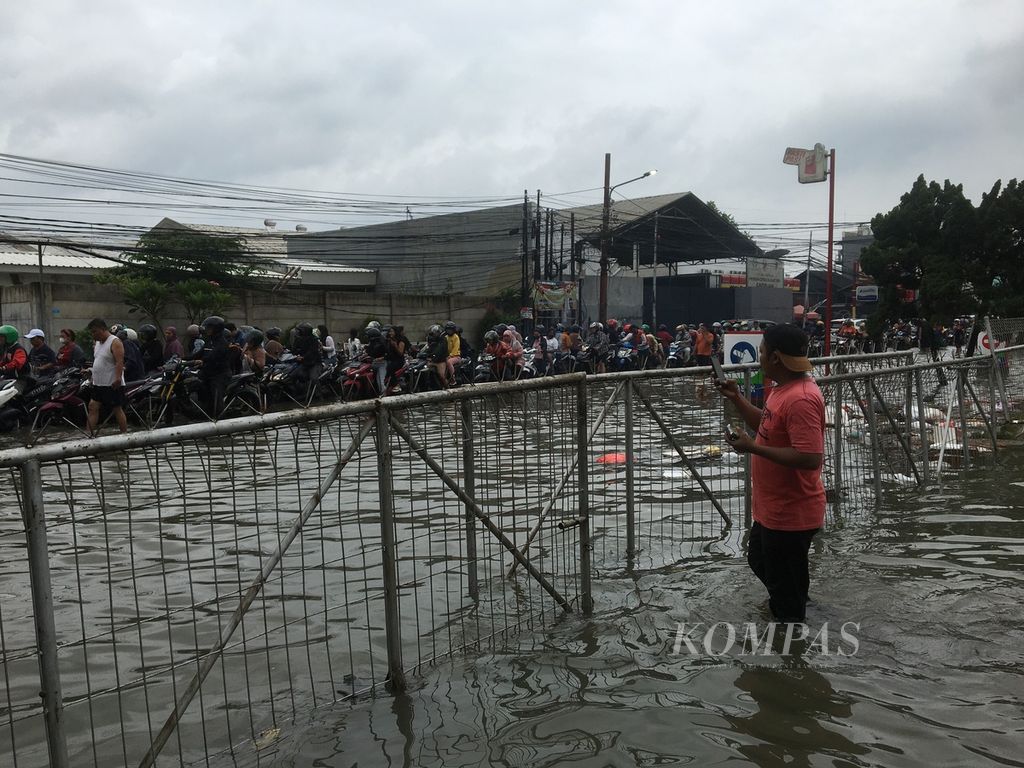 Eko menerjang banjir di Jalan Wana Mulya Utama, Karang Mulya, Karang Tengah, Kota Tangerang, Banten, demi datang ke TPS pada Rabu (14/2/2024) siang.