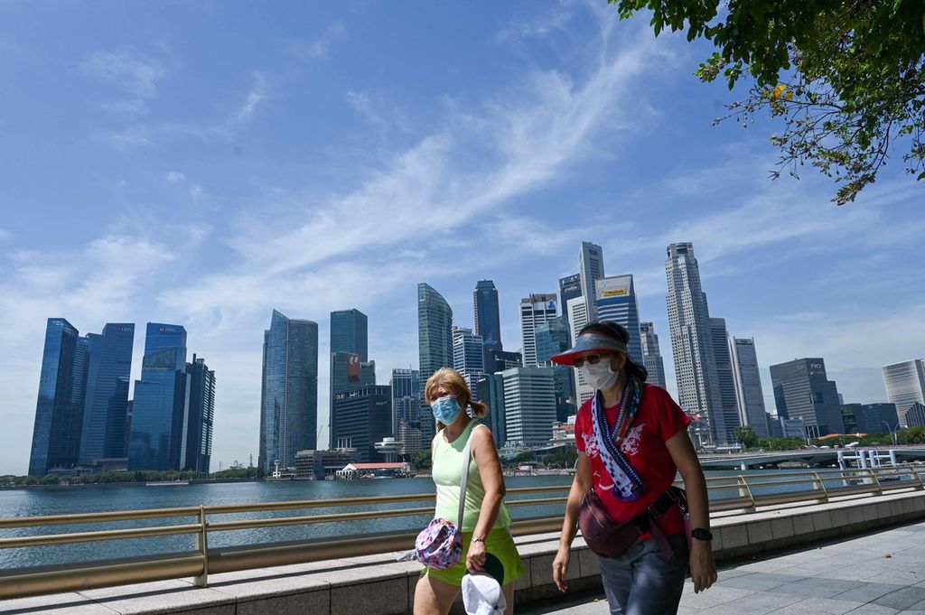 Warga berjalan di sepanjang Marina Bay dengan latar belakang pemandangan gedung-gedung pencakar langit di kawasan pusat bisnis di Singapura, Kamis (17/2/2022). 