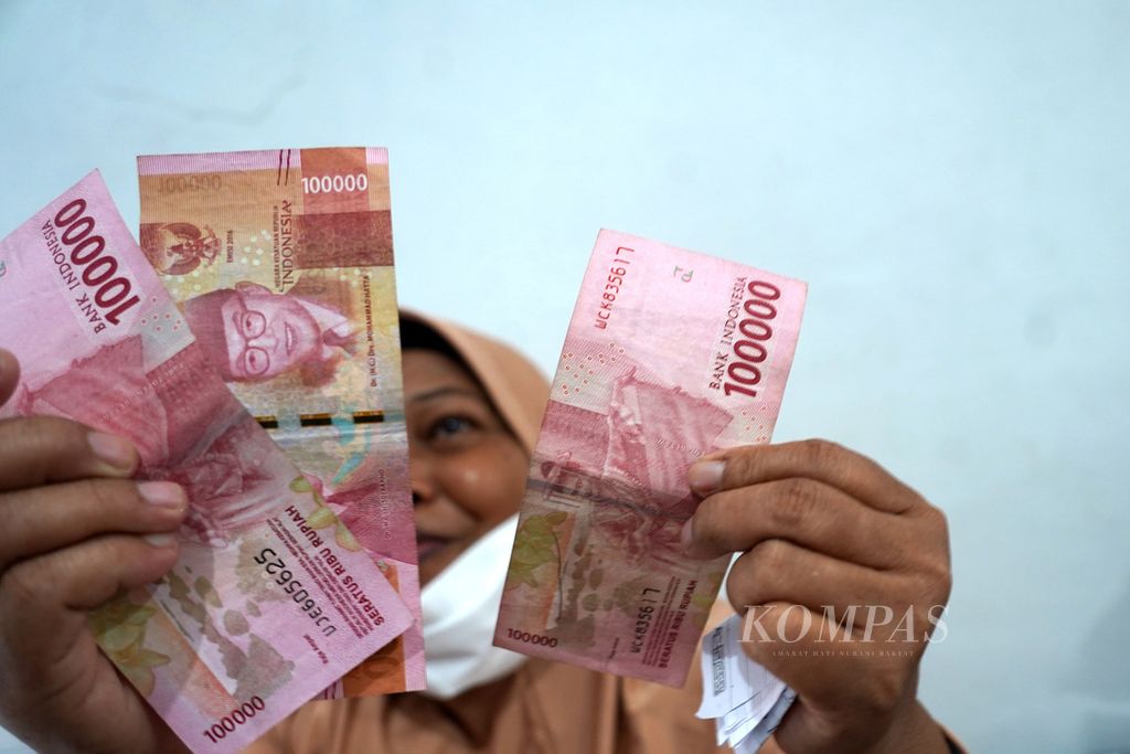 Seorang warga menunjukkan uang bantuan sosial pengalihan subsidi bahan bakar minyak yang diterimanya setelah pembagian di Aula Pos RW 001 Kelurahan Gambir, Kecamatan Gambir, Jakarta Pusat, Jumat (2/9/2022). 