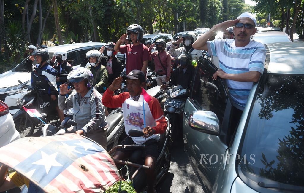 Pengendara berhenti sejenak dan memberi hormat kepada bendera Merah Putih di Jalan Polisi Istimewa saat peringatan detik-detik proklamasi memperingati HUT Ke-78 Kemerdekaan RI, Kota Surabaya, Kamis (17/8/2023).