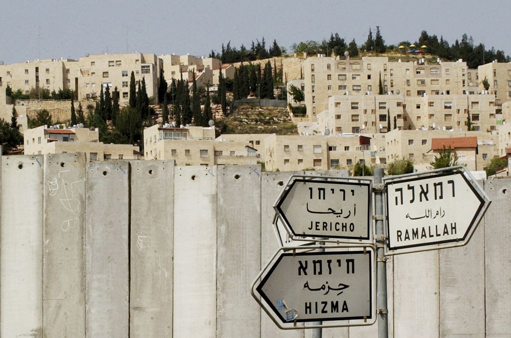 Foto yang diambil pada 14 April 2005 memperlihatkan papan penunjuk jalan di depan tembok pembatas pemukiman Yahudi dan wilayah Palestina di Hizma, Yerussalem. Lembaga advokasi global, Selasa (1/2/2022) mengeluarkan laporan yang menyebut bahwa Pemerintah Israel telah menjalankan kebijakan apartheid terhadap rakyat Palestina. 