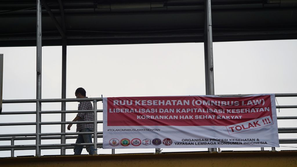 Warga melewati spanduk penolakan RUU Kesehatan di Tebet, Jakarta Selatan, akhir November 2022. 