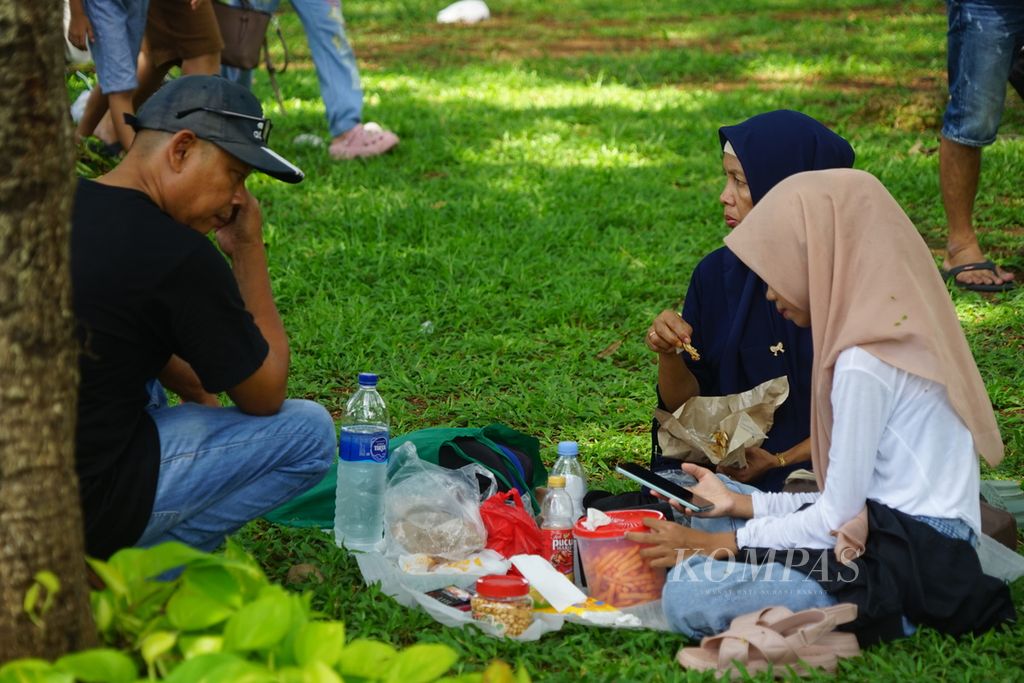 Warga berpiknik di area taman Monumen Nasional, Jakarta Pusat, pada Minggu (23/4/2024).