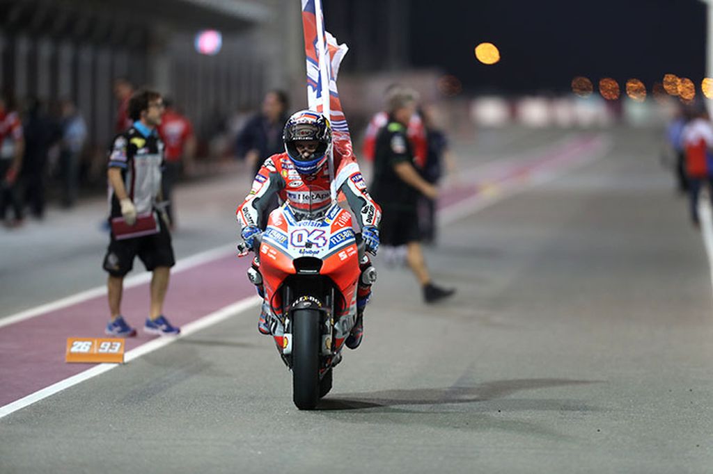 Pebalap tim Ducati, Andrea Dovizioso, melakukan victory lap dengan membawa bendera setelah memenangi seri pembuka MotoGP 2018 di Sirkuit Losail, Qatar, Minggu (18/3). Dovizioso musim ini menjadi favorit juara dunia.
