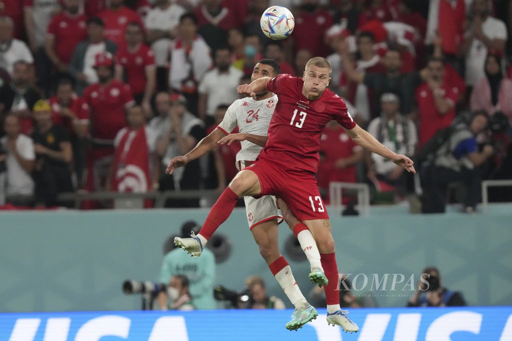 Pemain Denmark Rasmus Kristensen berebut bola dengan pemain Tunisia Ali Abdi saat bertanding di babak fase grup C Piala Dunia 2022 di Stadion Education City, Qatar, Selasa (22/11/2022). Pertandingan berakhir imbang 0-0. 