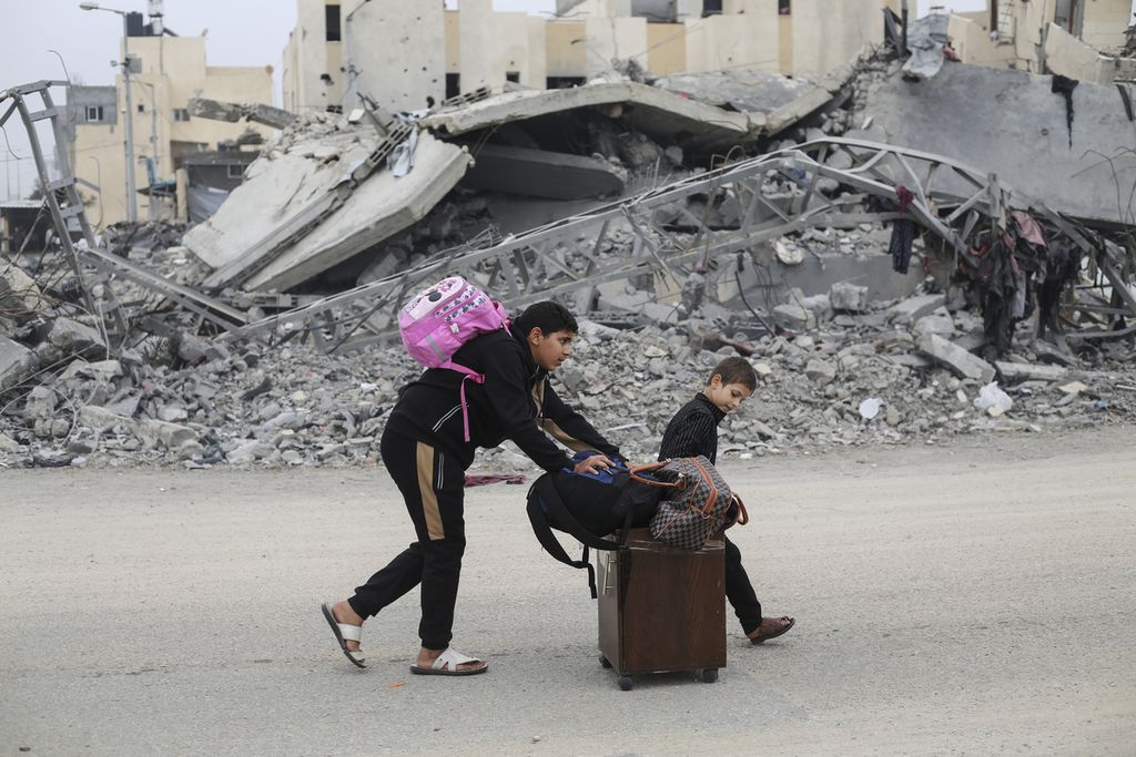 Dua bocah laki-laki warga Palestina membawa koper dan tas yang berisi pakaian dan barang lainnya. Mereka mencari lokasi yang aman dari kemungkinan serangan Israel di Rafah, Jalur Gaza, Selasa (5/12/2023).