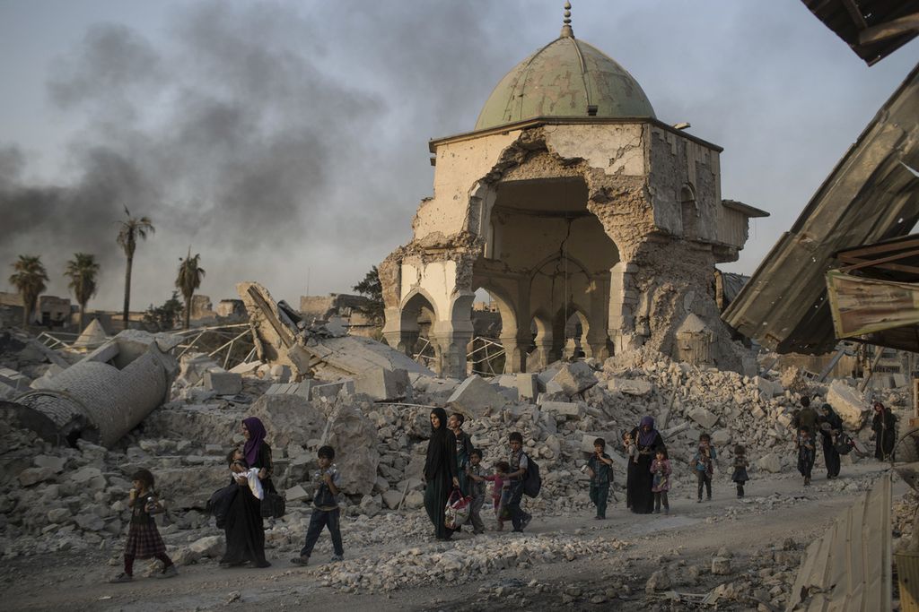 Dalam  foto yang diambil, Selasa (4/7/2017), warga sipil Irak berjalan melintasi Masjid Agung Al-Nuri yang rusak berat dalam pertempuran antara pasukan Pemerintah Irak dan kelompok NIIS. Organisasi Pendidikan, Ilmu Pengetahuan, dan Kebudayaan PBB (UNESCO), Sabtu (29/6/2024), mengumumkan temuan lima bom di dinding Masjid Agung. Bom tersebut merupakan sisa-sisa NIIS. 