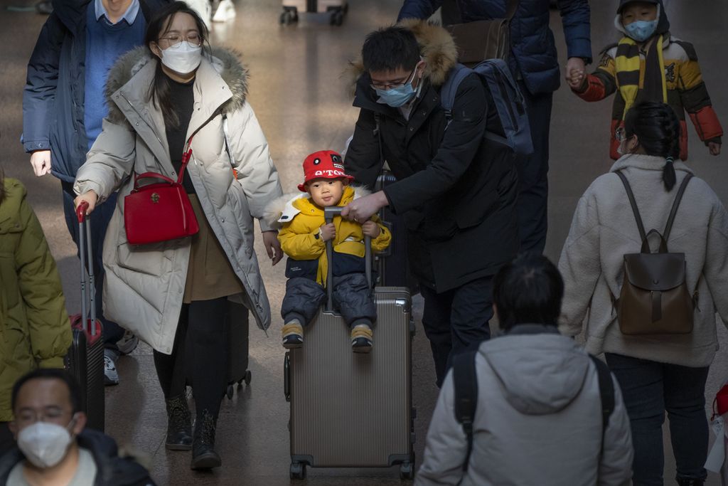 Seorang bapak mendorong koper yang dinaiki anaknya di Stasiun Kereta Api Beijing Barat di Beijing, Rabu, 18 Januari 2023. Populasi yang telah mencapai puncaknya dan perlahan menyusut akan menimbulkan tantangan baru bagi para pemimpin China.