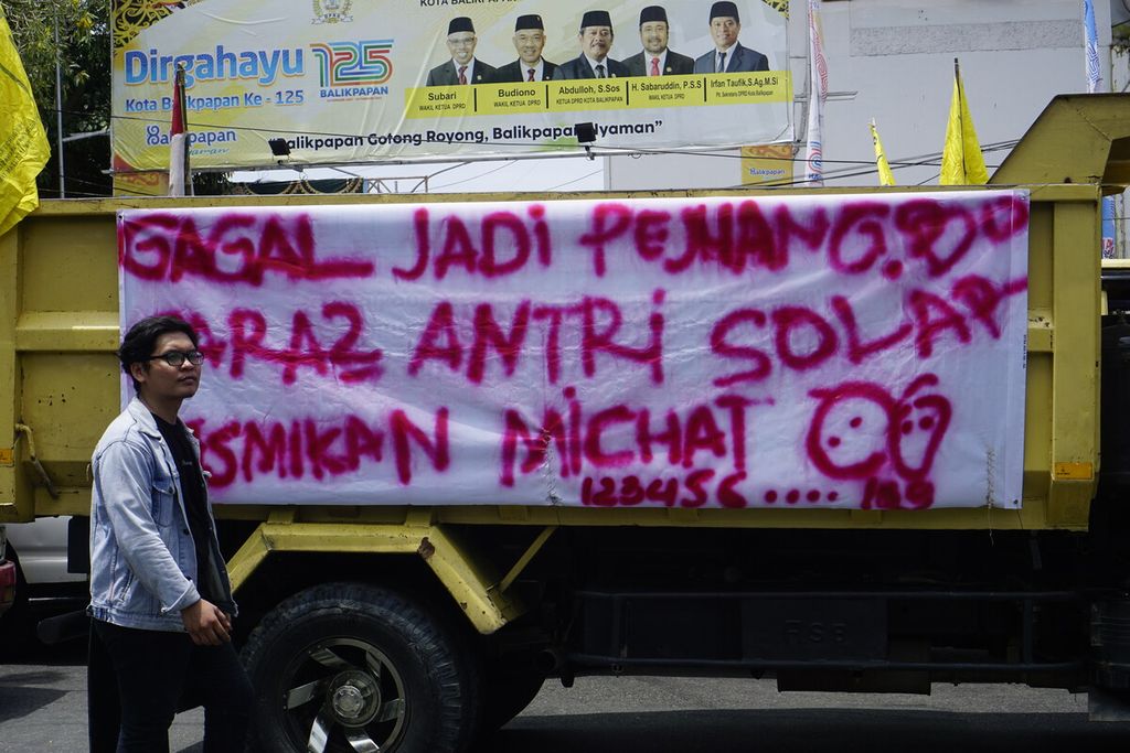 Sopir truk membentangkan spanduk tuntutan di bak truk saat berunjuk rasa di depan Kantor Wali Kota Balikpapan, Kalimantan Timur, Rabu (30/3/2022). Sedikitnya 250 truk dibawa dalam demonstrasi menuntut distribusi merata solar bersubsidi ini.