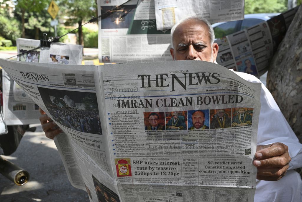 Seorang warga membaca sebuah surat kabar di Islamabad pada 8 April 2022. Tekanan ekonomi dan politik membawa Pakistan pada kondisi tidak stabil yang berujung pada penggulingan pemerintahan Perdana Menteri Imran Khan.  