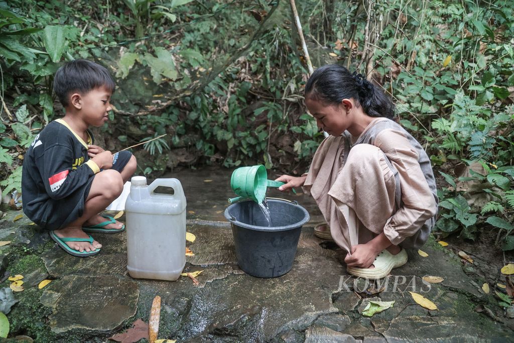 Mila (13), bersama adiknya mencari air bersih untuk kebutuhan air minum dan memasak di mata air 'Sumur Geulis' di Kampung Oteng, Desa Padasuka, Lebak, Banten, Senin (18/9/2023). Sumur Geulis yang berada di dalam hutan menjadi sumber air utama bagi warga kampung Oteng saat musim kemarau seperti saat ini. Sumur-sumur warga sudah kering sejak dua bulan yang lalu. 