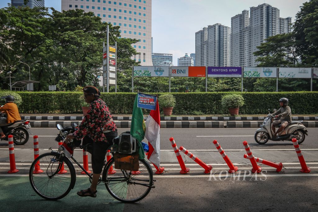 Seorang pesepeda melintasi <i>stick cone</i> pembatas lajur sepeda yang rusak di Jalan RM Margono Djojohadikoesoemo, Jakarta Pusat, Minggu (12/3/2023).