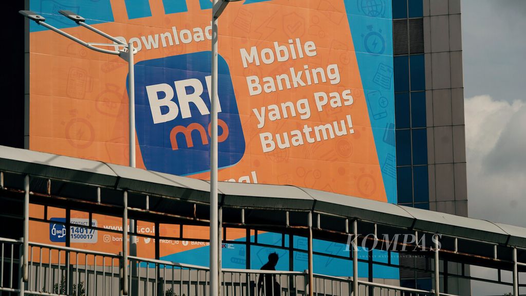 Warga melintasi baliho ajakan untuk mengunduh aplikasi digital BRI di Jalan Sudirman, Jakarta Pusat, Minggu (6/2/2022). 