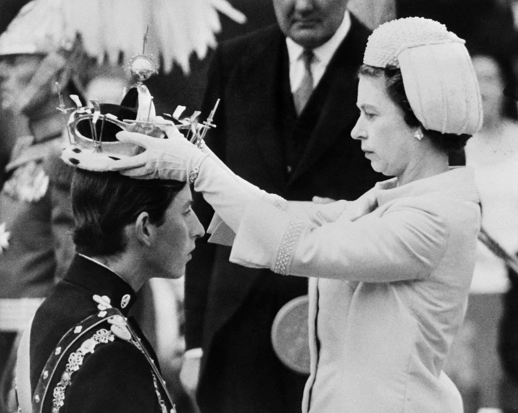 Foto tanggal 1 Juli 1969 ini memperlihatkan Ratu Elizabeth II memasangkan mahkota di kepala putranya, Pangeran Charles, yang saat itu ditetapkan sebagai pangeran baru Wales di Caernarfon. 