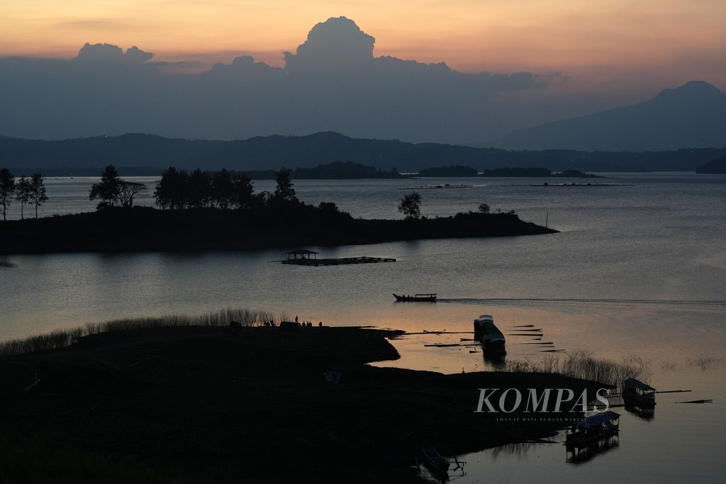 Siluet warga memancing ikan dan perahu di Waduk Jatigede di Desa Ciranggem, Kecamatan Jatigede, Kabupaten Sumedang, Jawa Barat, Minggu (4/8/2024). Selain menampung cadangan air dan pembangkit listrik tenaga air, waduk buatan seluas 4.983 hektar ini juga menjadi tempat pariwisata.